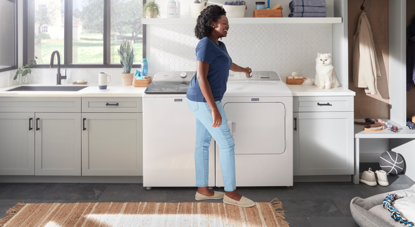Person standing in front of a white Maytag® top load washer and dryer set