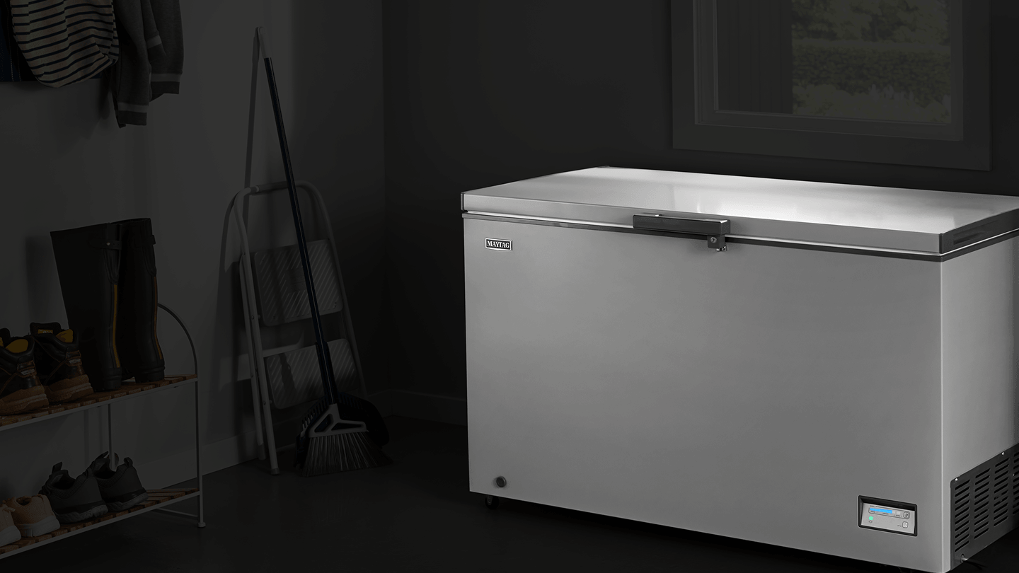 An open Maytag® chest freezer in a garage.