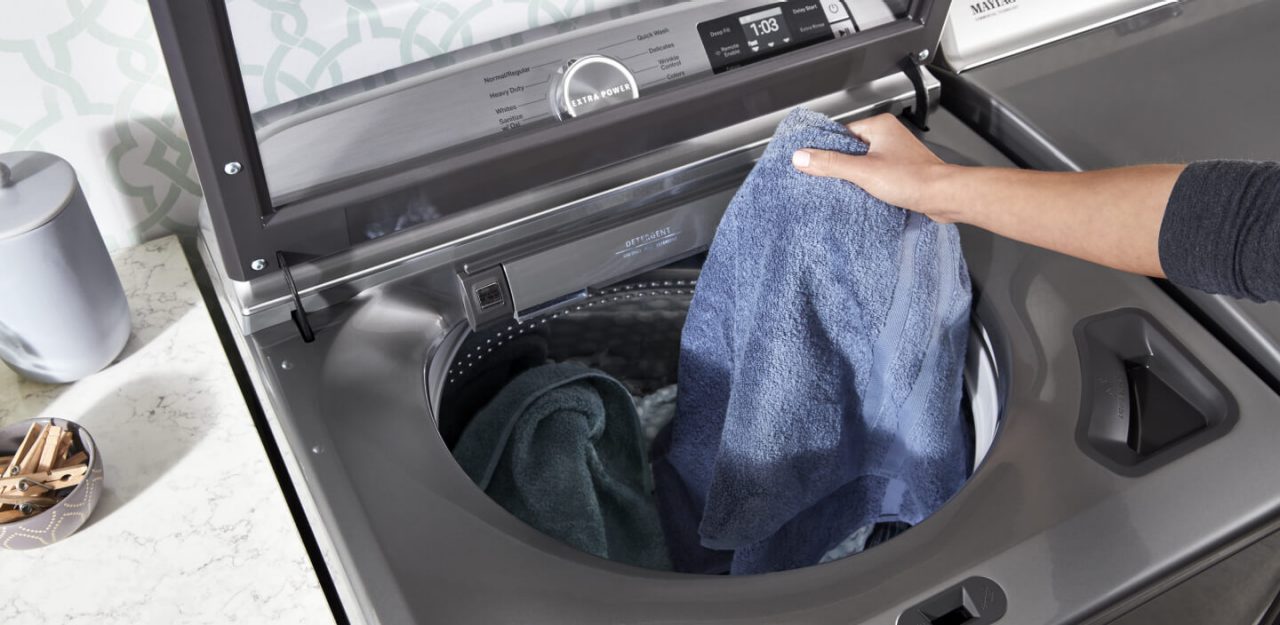 Person placing a towel in the washing machine
