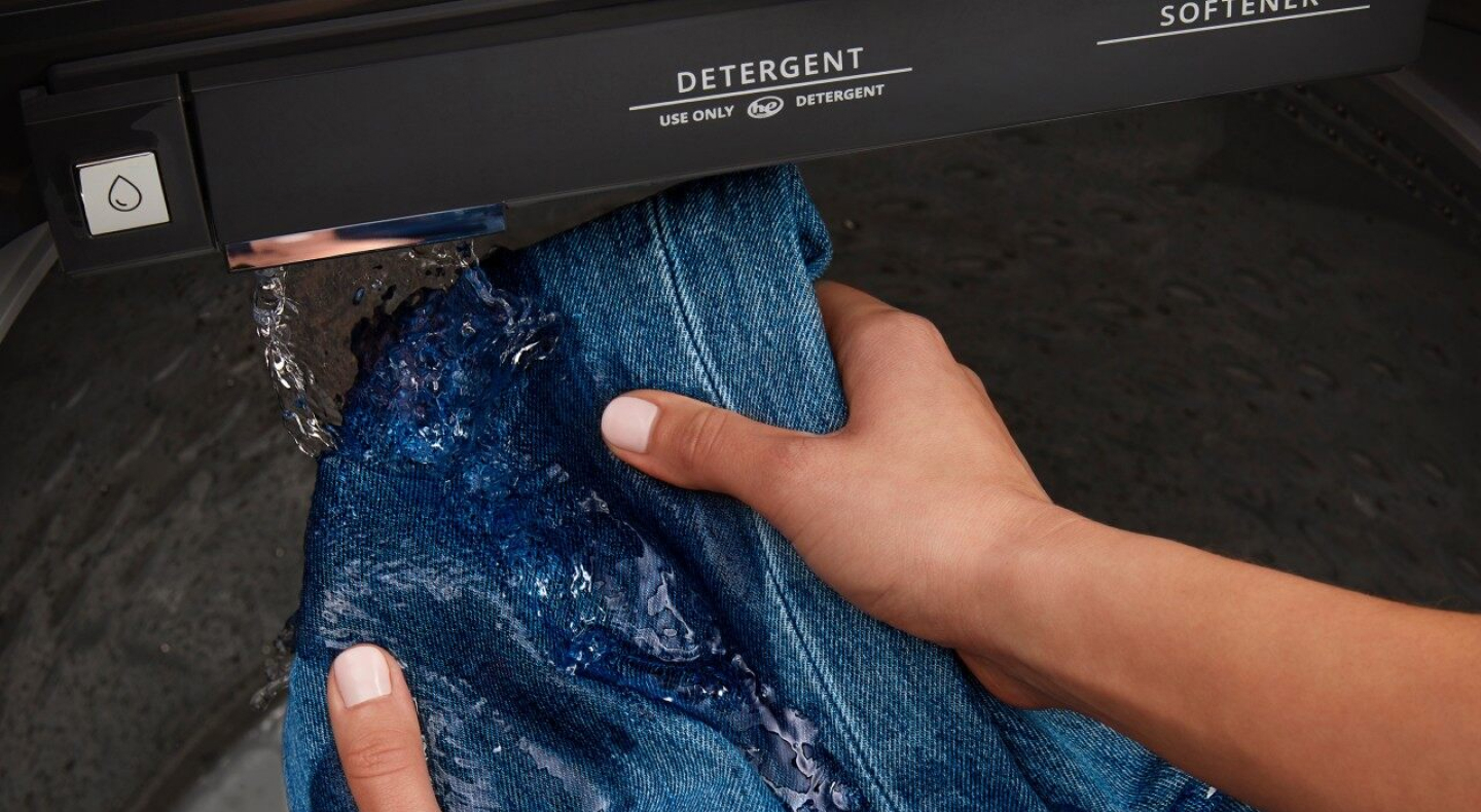 Hands pre-treating denim with built-in water faucet