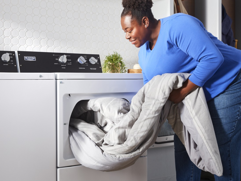 Person unloading comforter from commercial-grade dryer