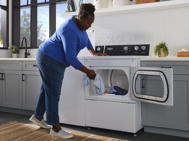 Person loading clothes into a commercial-grade dryer