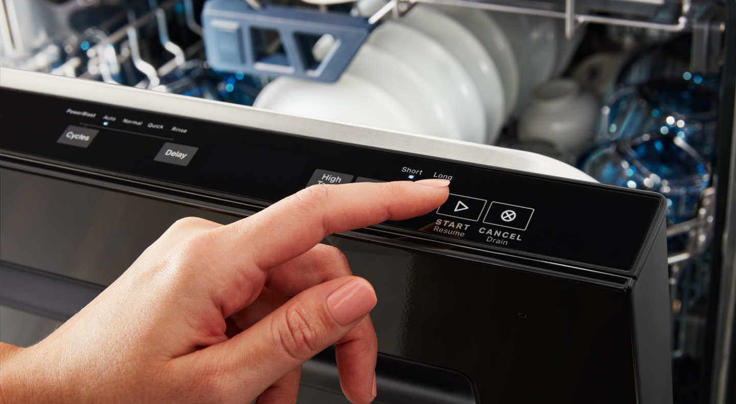 Person selecting start button on a top control dishwasher