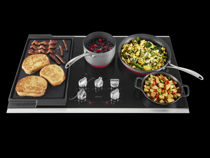 An electric cooktop cooking five different dishes at once