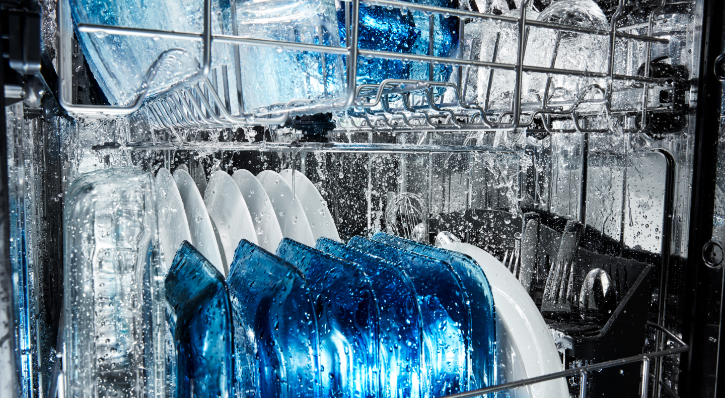 Dishes being rinsed on the top and bottom racks of a dishwasher