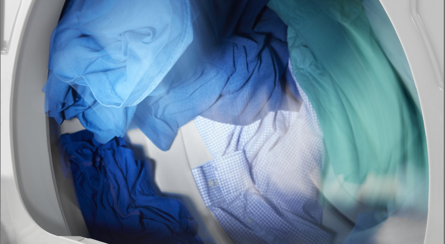 Blue and green colored clothes tumbling in dryer