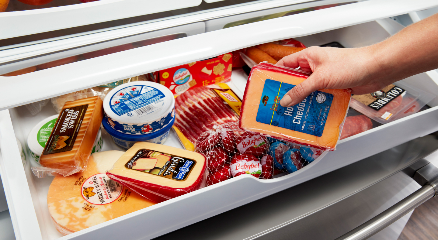 Maytag brand refrigerator’s deli drawer stocked with meats and cheeses