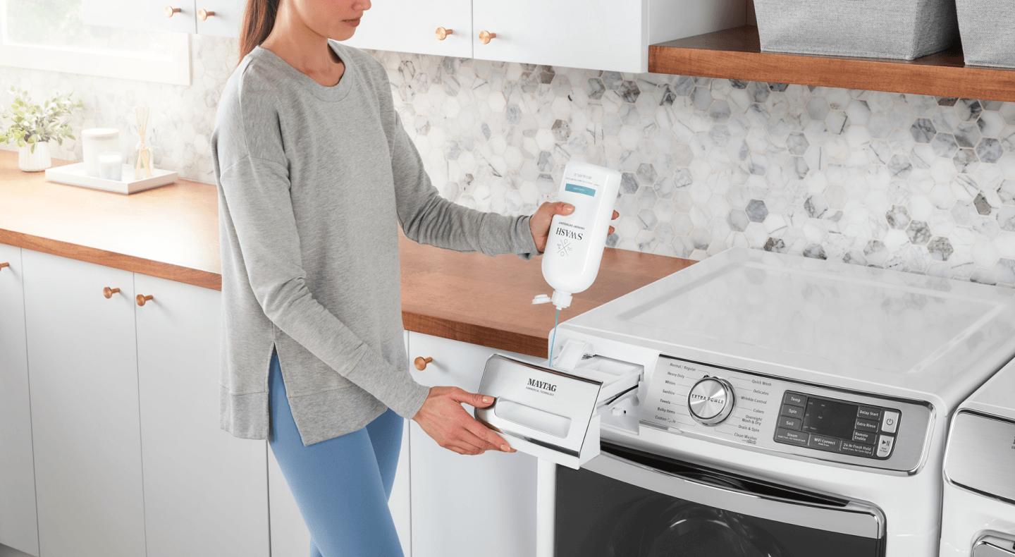 A person filling a detergent dispenser with Swash® Laundry Detergent