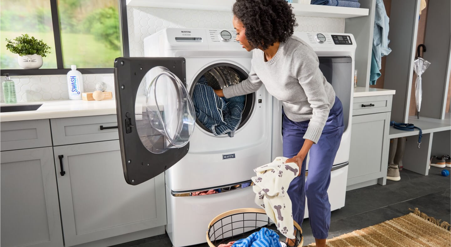 Person loading clothing into a front load Maytag® washer