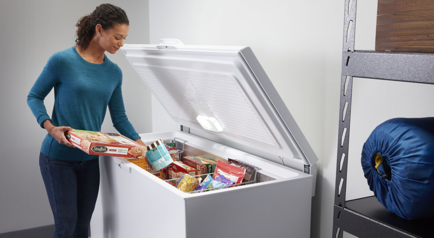 Person putting frozen pizza in freezer