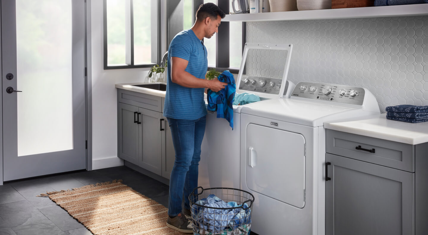 A person putting laundry into a Maytag® washer