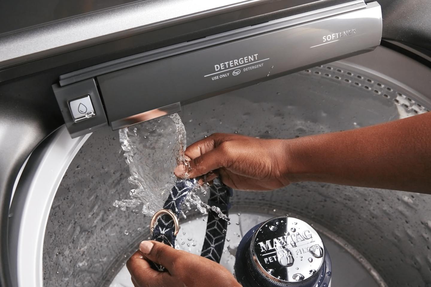 Person washing dog’s neck collar with Maytag® washer’s built-in faucet