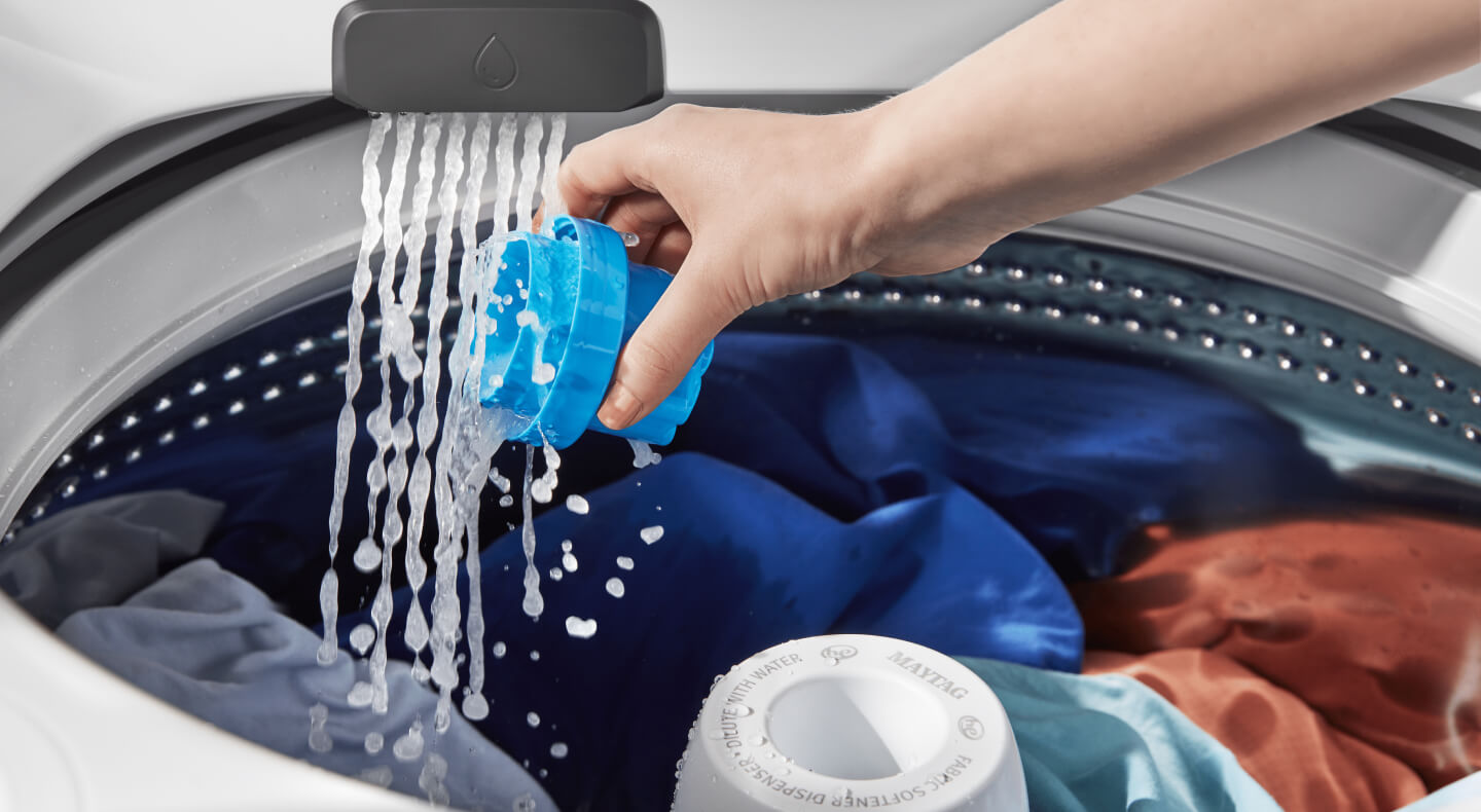 Person rinsing a detergent cap inside the washing machine
