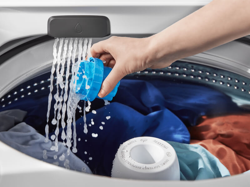 Person rinsing a detergent cap inside the washing machine