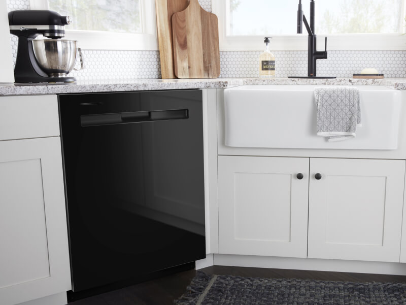A black Maytag® dishwasher surrounded by white cabinetry