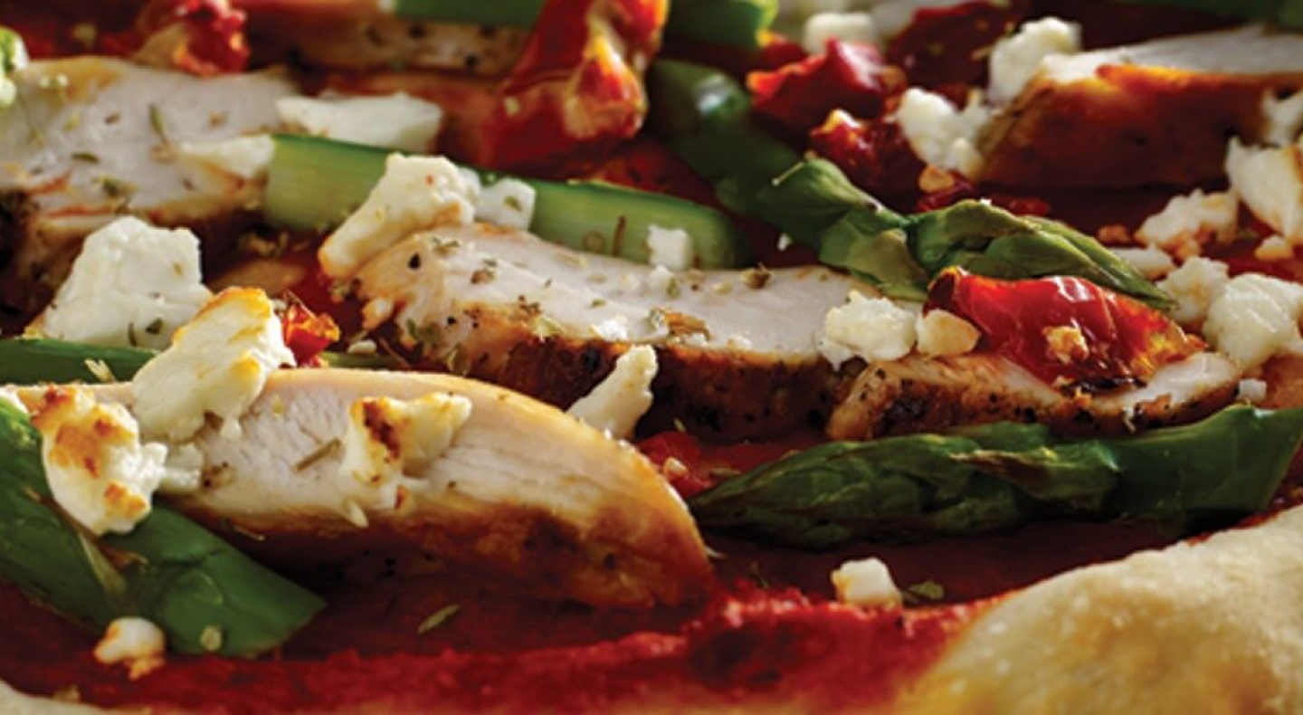 A close-up of chicken and vegetable pizza toppings