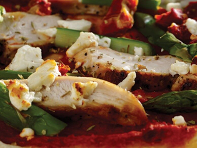 A close-up of chicken and vegetable pizza toppings