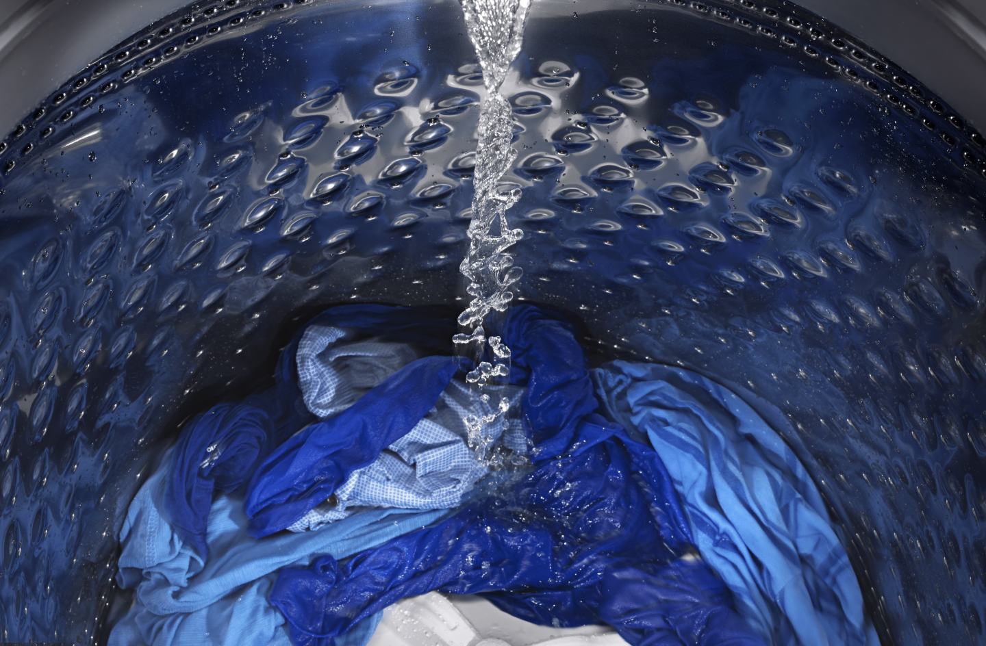Water pouring into washer full of clothes