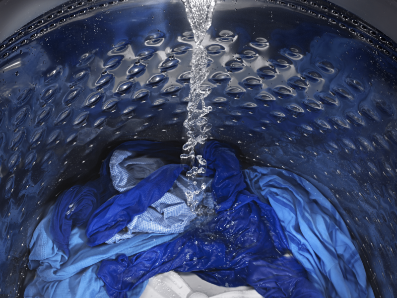 Water pouring into washer full of clothes