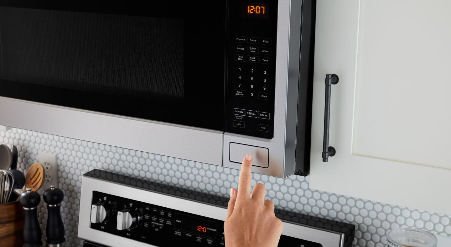 Person pressing open button on microwave