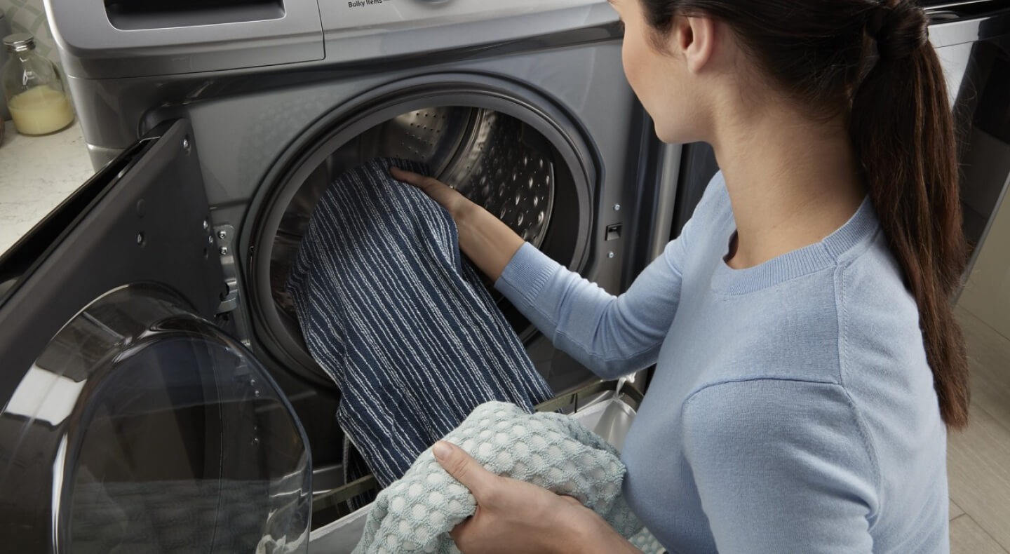 A person adding laundry to a Maytag® front load washer