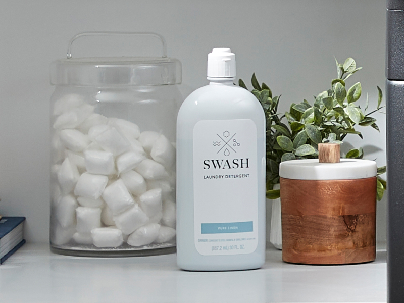 Swash® detergent next to a glass jar of laundry pods