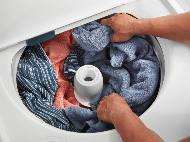 Person loading towels into a top load washer