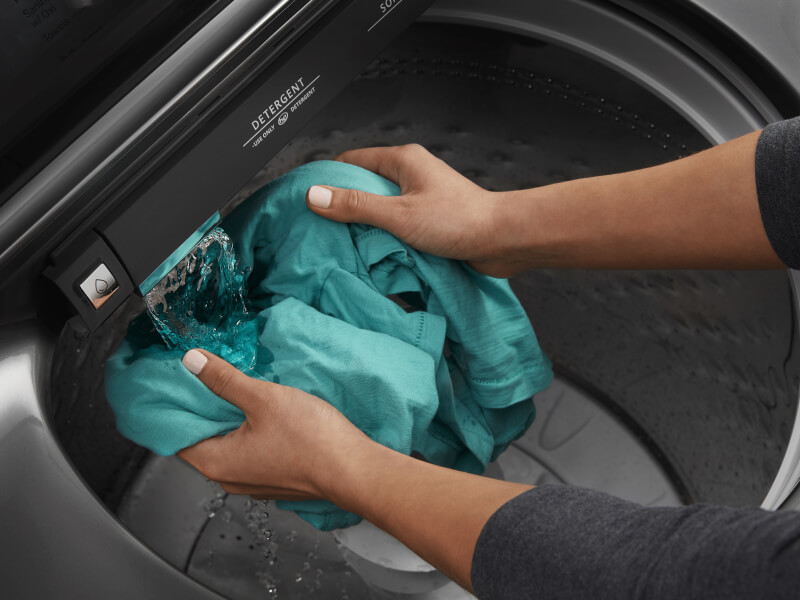Person rinsing blue clothes in washing machine