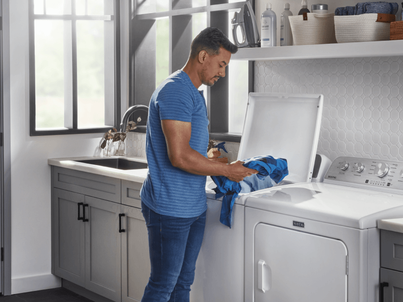 Person loading blue clothes in washing machine