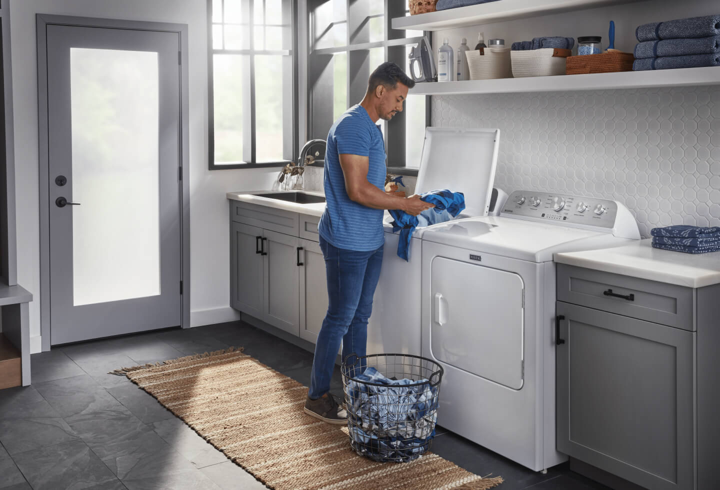 Person loading blue clothes in washing machine