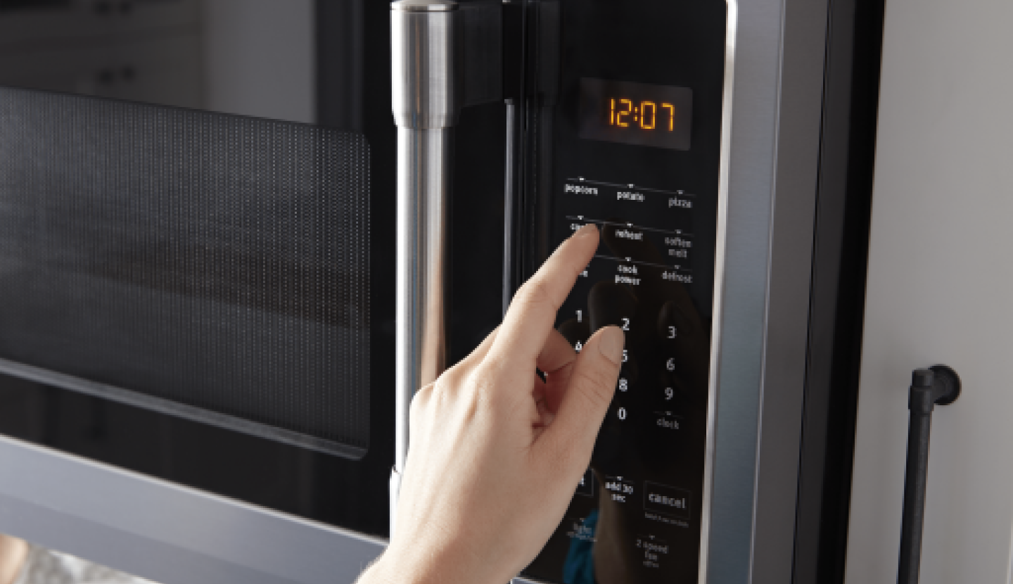Person pushing buttons on a microwave keypad