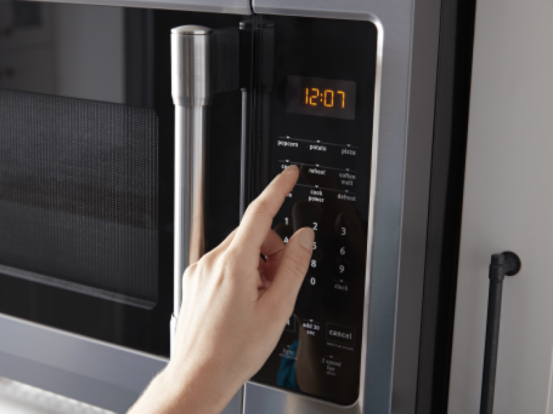 Person pushing buttons on a microwave keypad