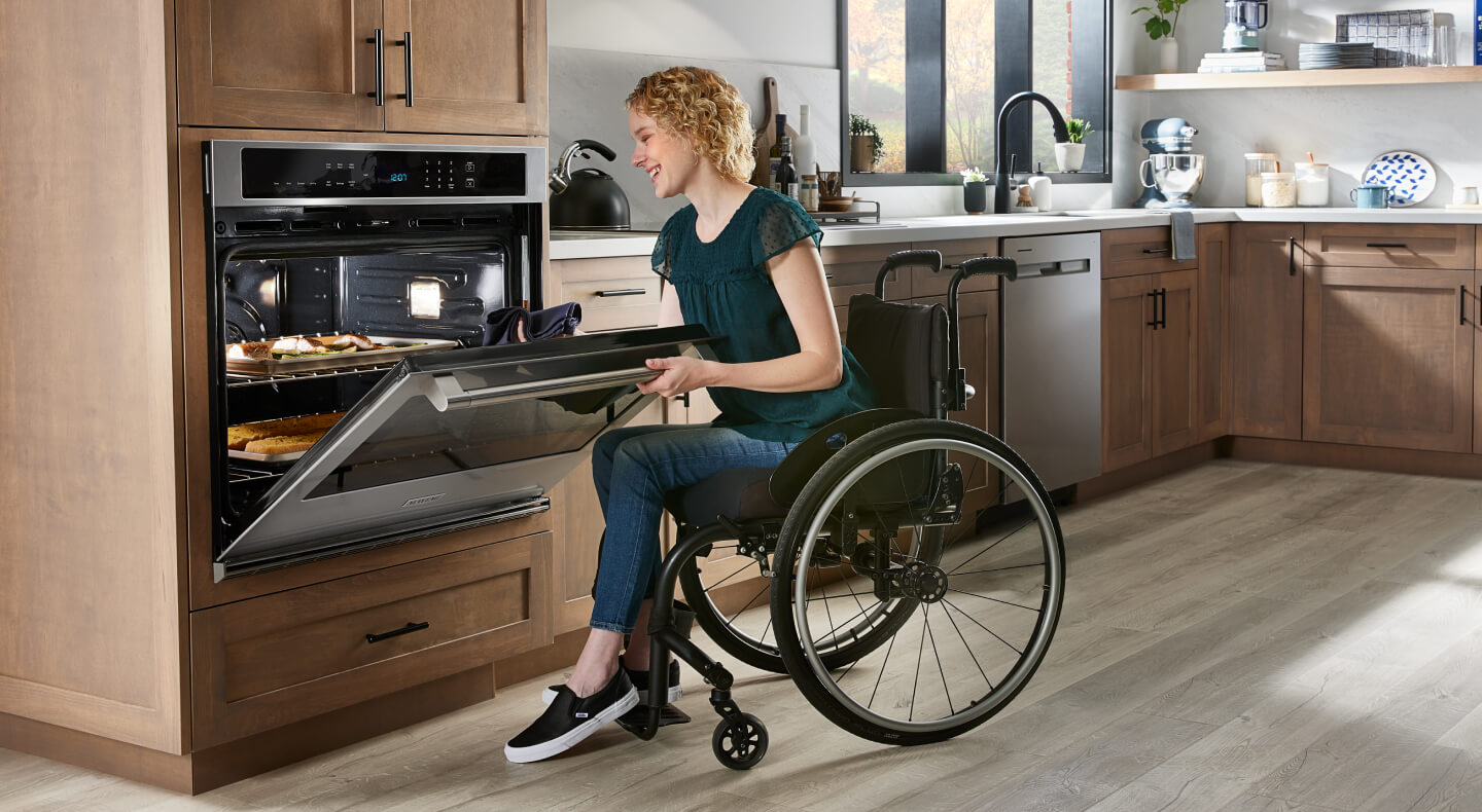 Person in wheelchair checking food in a Maytag® wall oven