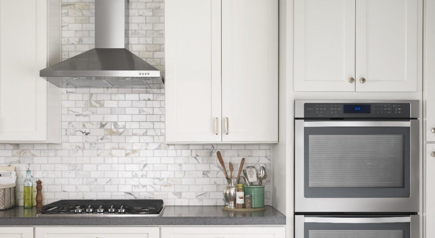 Stainless steel Maytag® range hood in a bright kitchen