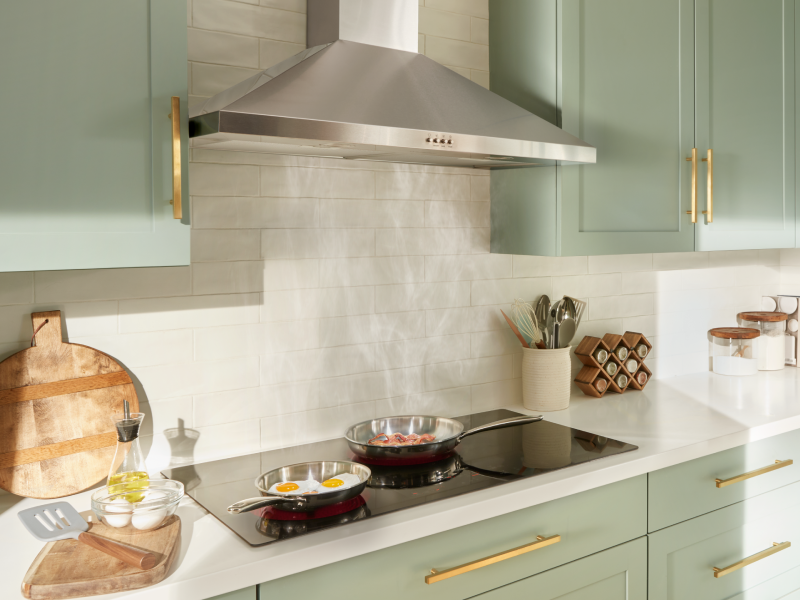 Stainless steel Maytag® range hood in a light green kitchen
