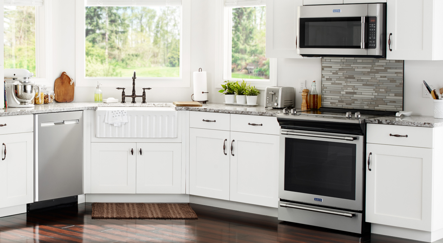 Various stainless steel appliances in a kitchen with white cabinetry