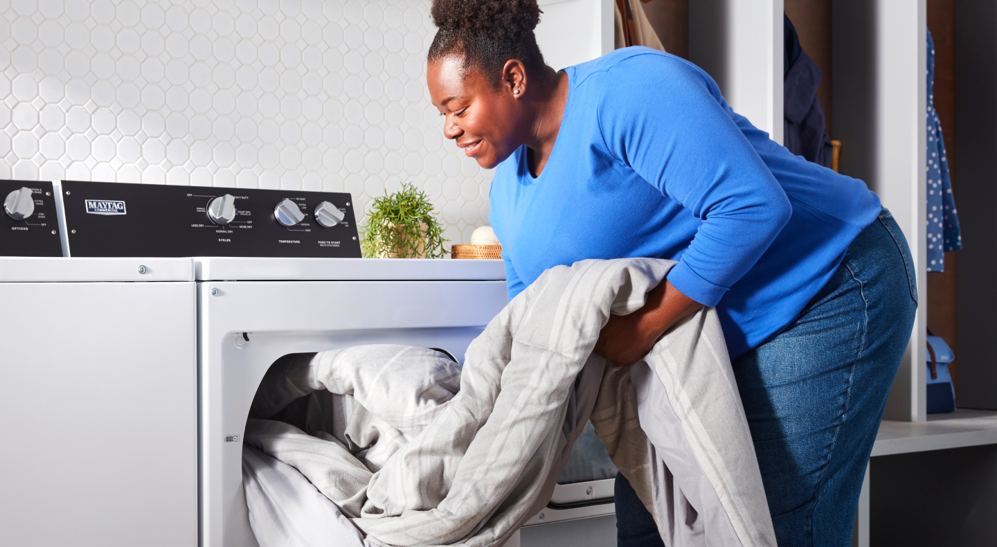 Person removing a blanket from a commercial-grade washer