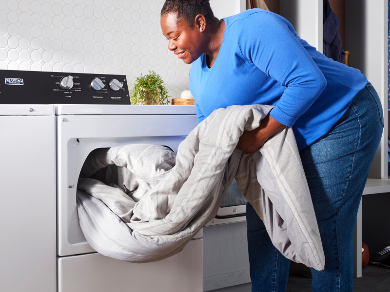 Person removing a blanket from a commercial-grade washer