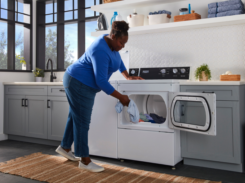 Person loading laundry into a commercial-grade dryer
