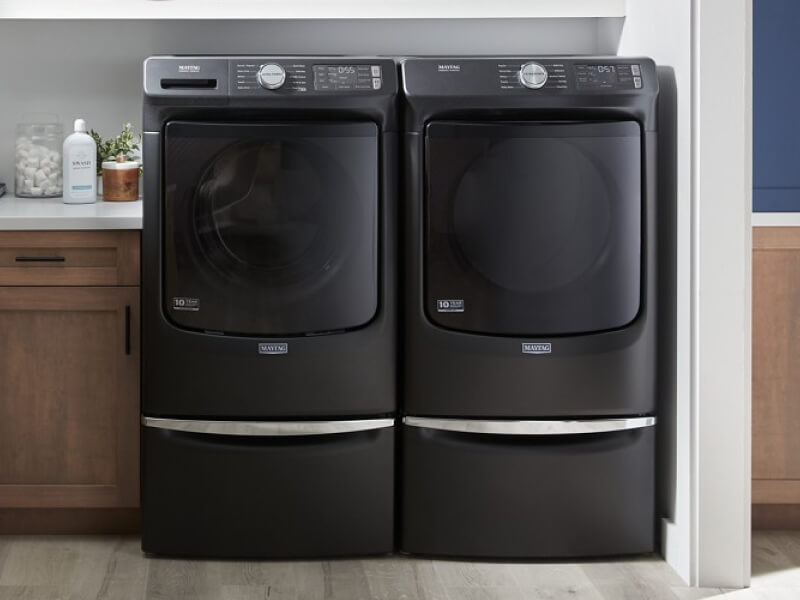 A Maytag® washer and dryer set in a laundry room with brown cabinetry