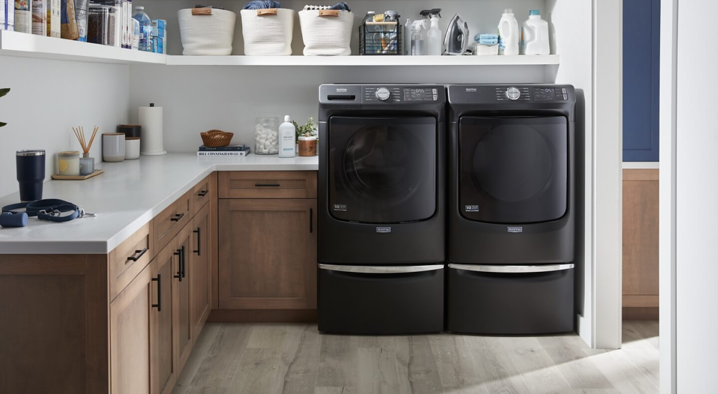 A Maytag® washer and dryer set in a laundry room with brown cabinetry
