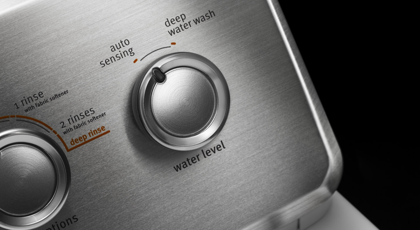 A closeup of a knob turned to “auto sensing” on a control panel of a Maytag® washer
