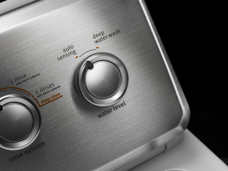 A closeup of a knob turned to “auto sensing” on a control panel of a Maytag® washer