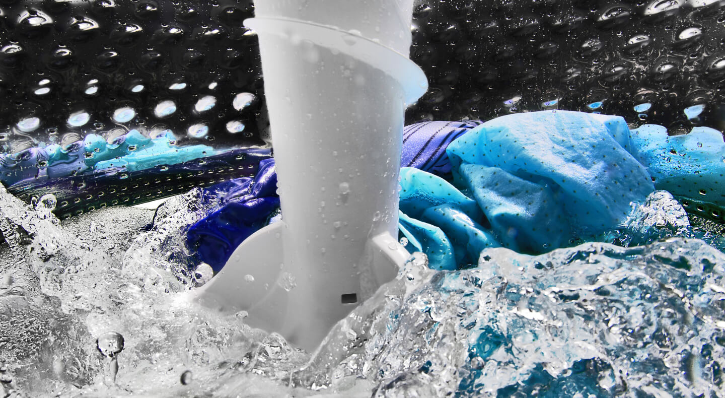 A closeup of laundry items spinning in water in a Maytag® washing machine drum
