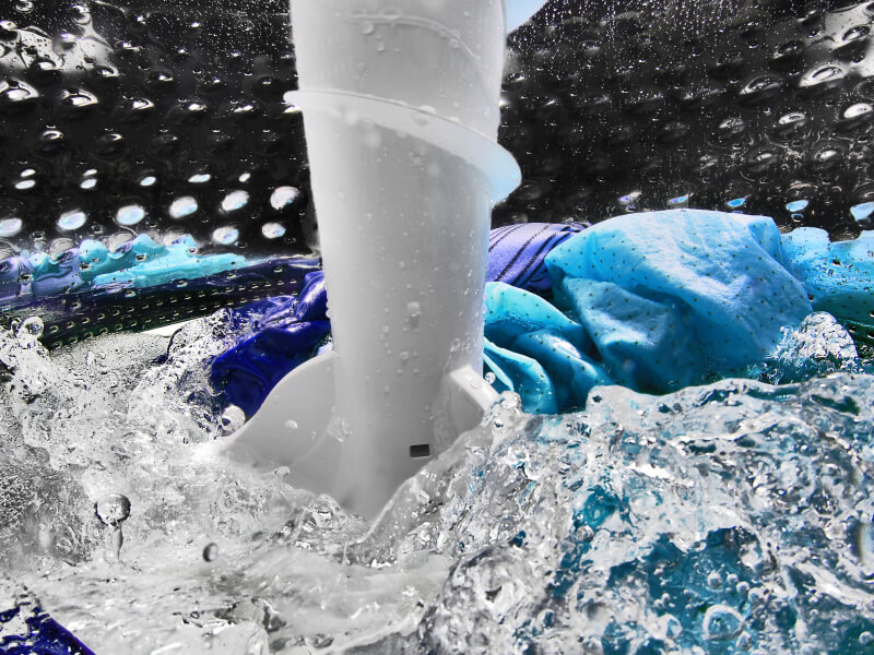 A closeup of laundry items spinning in water in a Maytag® washing machine drum