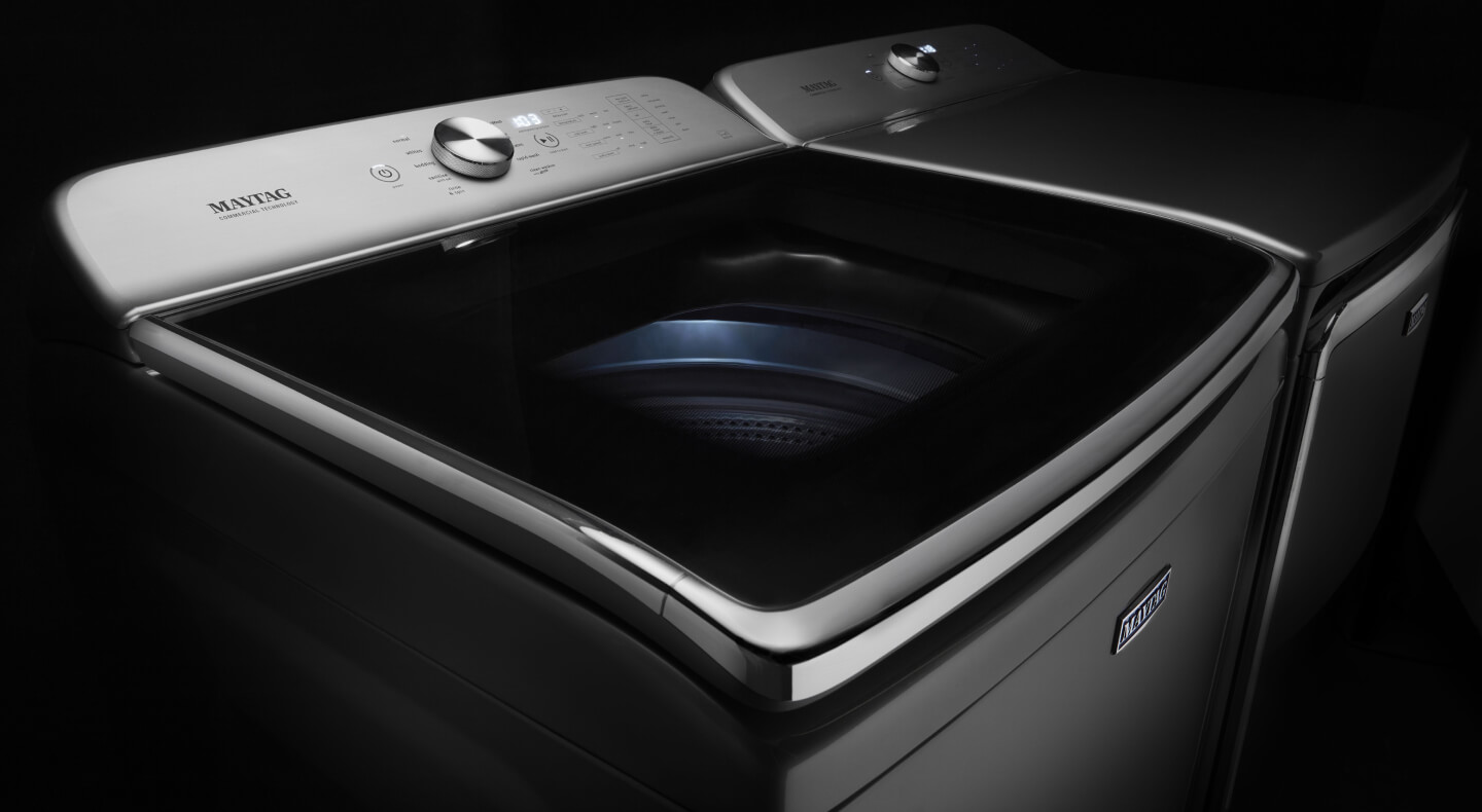 Maytag® stainless steel top load washing machine against a black background