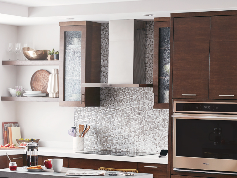 Kitchen with electric stovetop beneath wall mount canopy range hood
