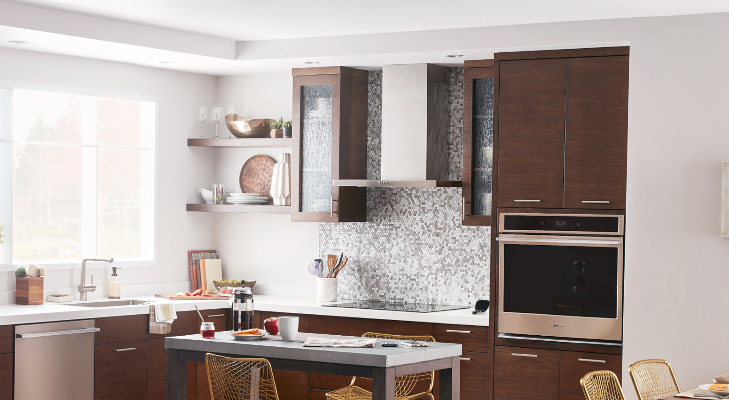 Kitchen with electric stovetop beneath wall mount canopy range hood