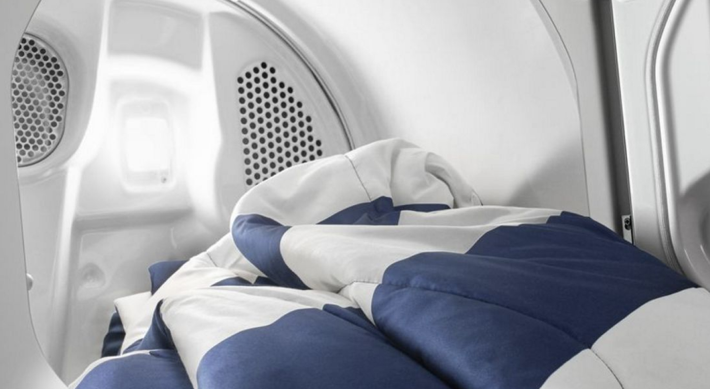 An open Maytag® dryer with a blanket coming out.