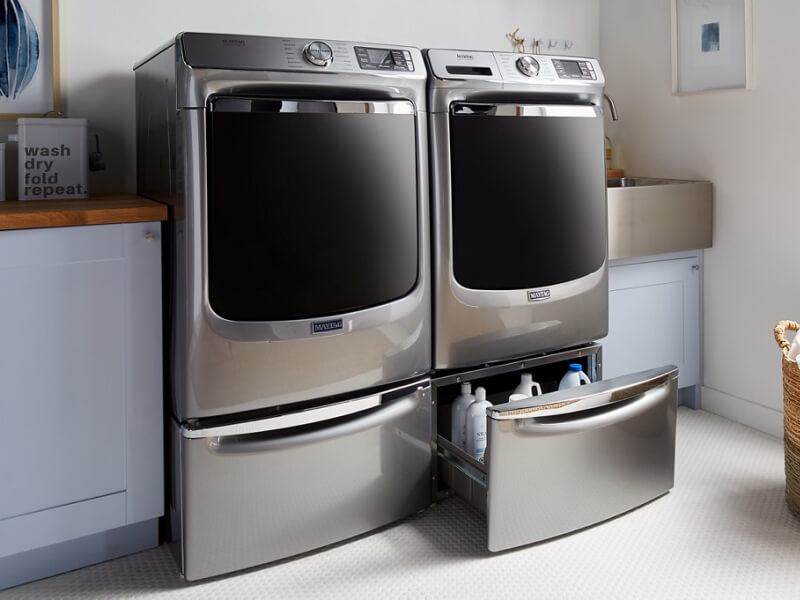 Maytag® front load laundry pair on pedestals with one pedestal drawer open